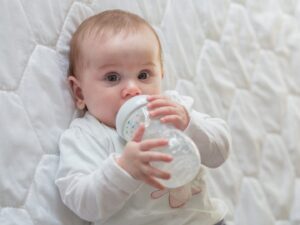 Un bambino beve il latte dal suo biberon