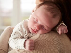 Sonno e reflusso _ Un neonato dorme sulla spalla della mamma