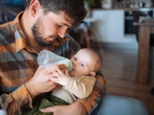 Un papà dà il latte al suo neonato con il biberon