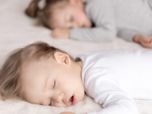 Le fasi di sonno dei bambini: due piccoli dormono uno di fianco all'altro sul letto