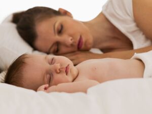 Il sonno di una mamma che riposa distesa sul letto accanto al suo bambino