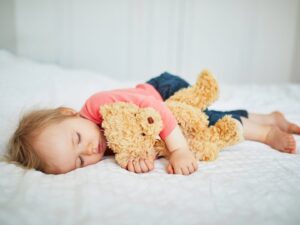 L'oggetto speciale del sonno: una bambina dorme abbracciata al suo orsetto di peluche