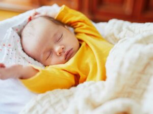 Il sonno di un bambino che si alza durante la notte: un piccolo si stira le braccia mentre dorme nel suo letto