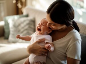 coliche: un bimbo, in braccio alla mamma, piange di dolore