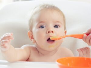 svezzamento: una bambina mangia imboccata dalla sua mamma