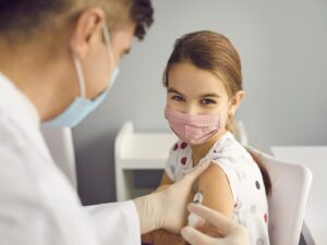 vaccini: una bambina, in ospedale, sorride mentre il dottore le inietta un vaccino