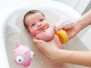 bagnetto: una mamma immerge il proprio piccolo nella vasca tenendolo in modo accurato.